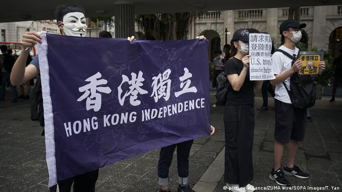 Hong Kong pro-democracy protesters wear masks and hold up a flag calling for independence