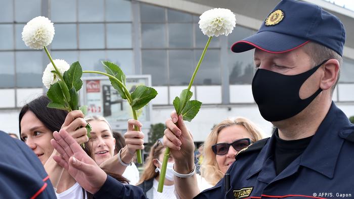 Mulheres abraçam policiais e colocam flores em seus equipamentos de proteção