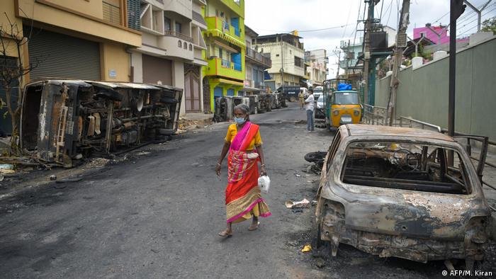 Masked woman walks among burnt cars (AFP/M. Kiran)