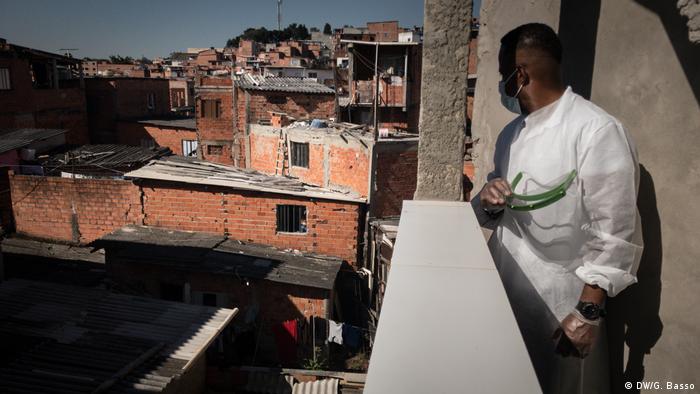 Homem de máscara observa favela de Paraisópolis, em São Paulo
