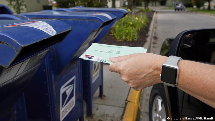 Mão coloca carta numa caixa de correio