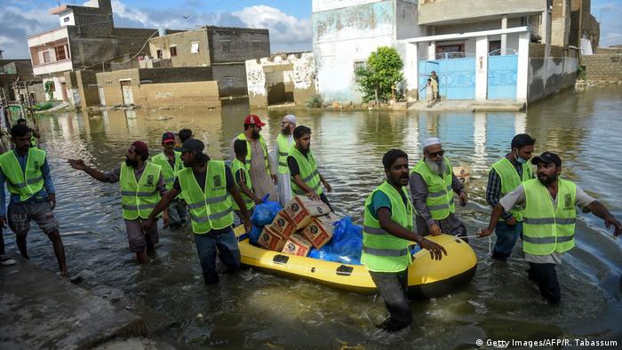 Volunteers distribute food to flood-affected residents at a flooded area after heavy monsoon rains in Pakistan's port city of Karachi on August 26, 2020