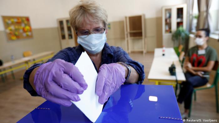 A woman puts her vote into a ballot box (Reuters/S. Vasiljevic)