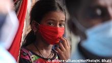 Indien Mumbai | Coronavirus: Mädchen mit Mundschutz beobachtet medizinisches Personal