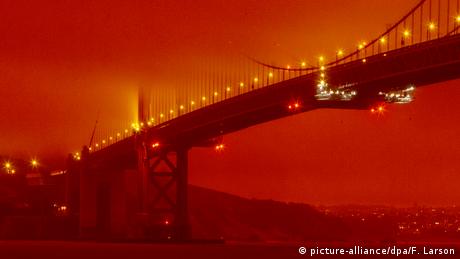 El puente Golden Gate en medio de una niebla anaranjada, a pleno día, y con el sol oculto por los residuos de los incendios en California.
