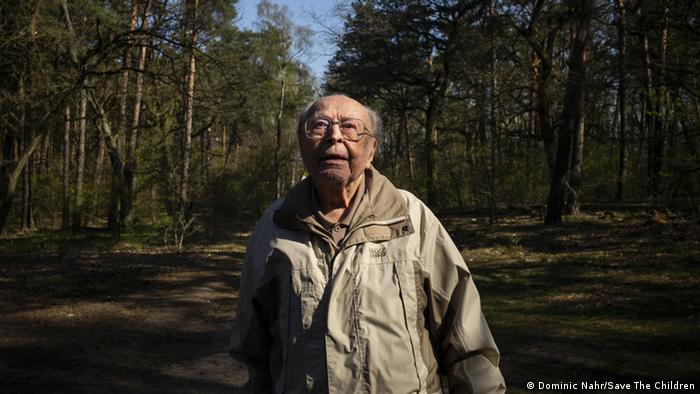 A senior man walking the forest looks up at the sky (Dominic Nahr/Save The Children)