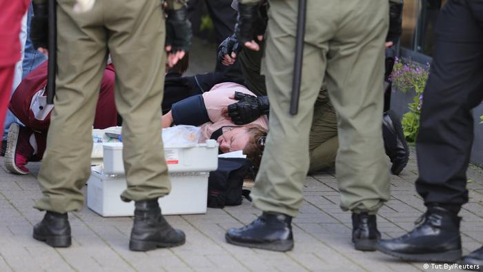 A woman lies on the floor while security stand around her