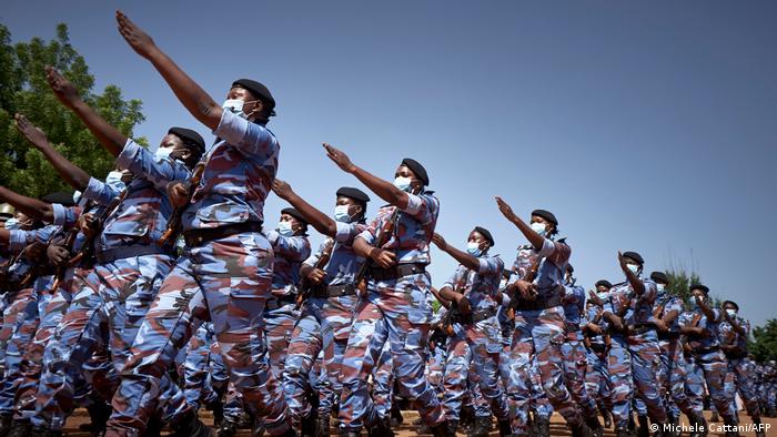 Soldatinnen und Soldaten marschieren in blau-brauner Uniform und mit Mundschutz (Michele Cattani/AFP)