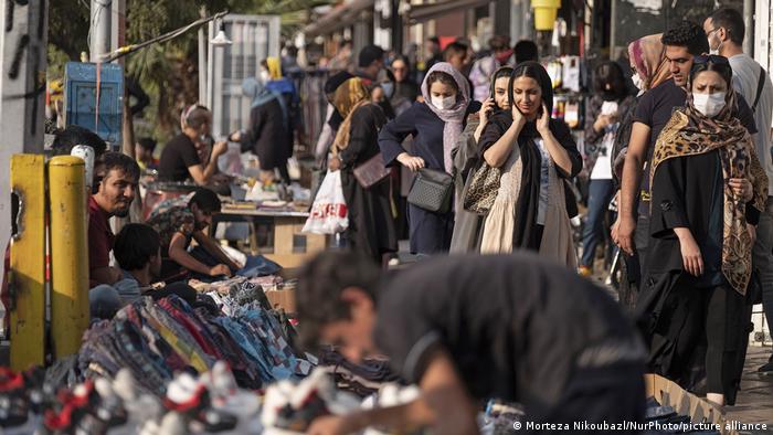 Iranian women who some of them wearing the protective face masks, walk past vendors along a street-side in Tehran's business district (Morteza Nikoubazl/NurPhoto/picture alliance)