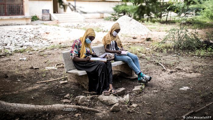 Two university students in Dakar sit on a bench with books on their laps