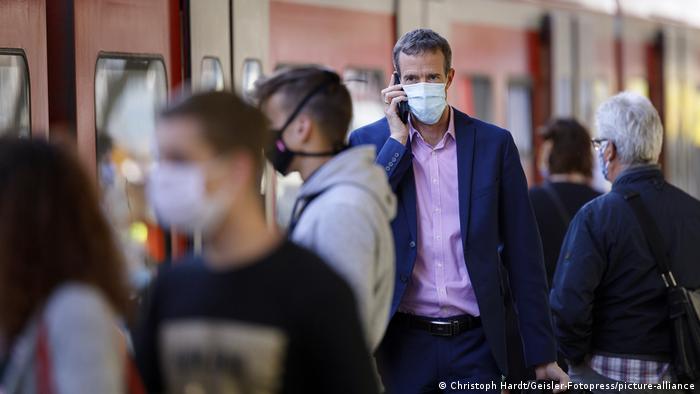 Pessoas de máscara em estação de trem em Colônia